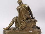 a bronze statue of a man sitting on a rock