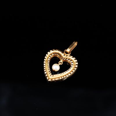 un pendentif en forme de cœur en or avec une perle au centre