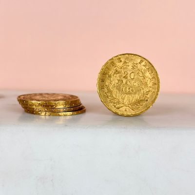 two gold coins sitting on top of a white table next to each other