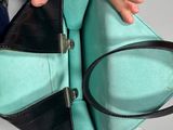 someone is holding a black and green purse in their hand