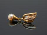 a close up of a pearl and gold pendant on a black surface