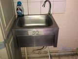 a sink in the corner of a bathroom with a faucet and soap dispenser on the wall