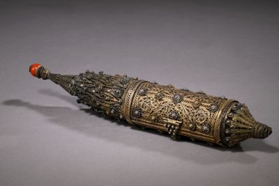an old silver and gold object with a red ball on it