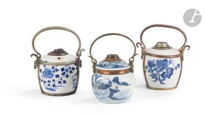 trois vases bleus et blancs munis d'anses, posés sur un fond blanc