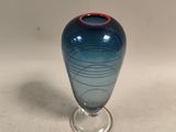 un vase bleu bordé de rouge posé sur une table