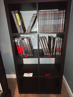 a black bookcase filled with dvds in a room