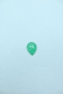 a green emerald gems on a white surface