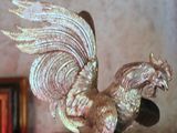 statue of a golden rooster on a wooden table in front of a wall