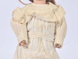 an old fashioned doll with a black hat and dress on a white surface
