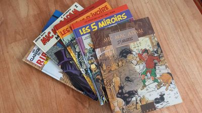 several children ' s books sitting on a wooden table with a cat