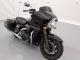 une moto noire garée dans une pièce aux murs blancs