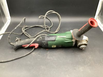 a green and red electric tool on a black surface