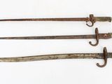 three old iron swords are displayed on a white surface