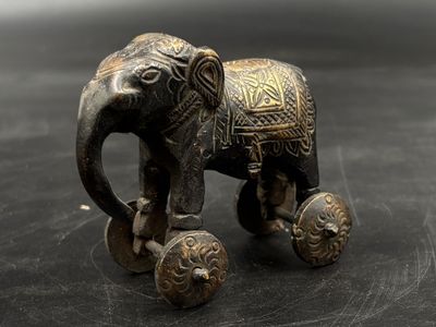 statue of an elephant on wheels on a black surface