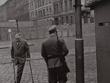 black and white photograph of two men walking down a cobblestone street