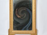 une photo d'un miroir à cadre doré présentant un motif en spirale