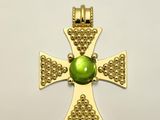 une image représentant une croix en or ornée d'une perle de verre verte