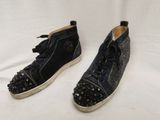 une paire de chaussures noires ornées de clous, posée sur une surface blanche