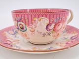 a pink tea cup and saucer on a white table