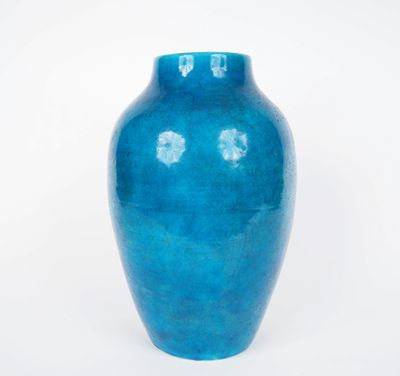 un vase bleu posé sur une surface blanche, sur fond blanc