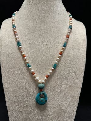 a white mannequin necklace with a turquoise pendant and pearls