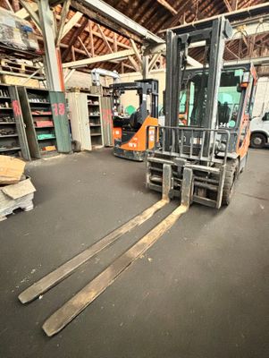 un chariot élévateur dans un entrepôt, avec des palettes au premier plan