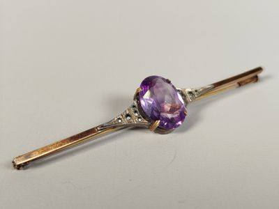 un gros plan sur une pierre violette montée sur une tige en or