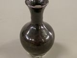 a small black vase sitting on a white table