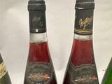 four bottles of wine are lined up on a white surface