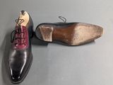 pair of men ' s black and red shoes on a gray surface