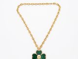 un collier à chaîne en or orné d'un pendentif en forme de fleur verte