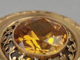 a close up of a gold ring with a yellow stone in the center