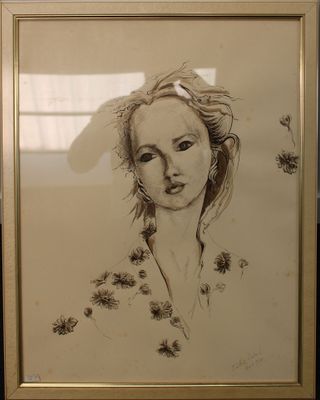 dessin représentant le visage d'une femme dans un cadre doré posé sur une table