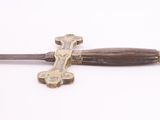a cross on the handle of a sword on a white surface