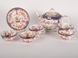 a tea pot, cups and saucer set on a table
