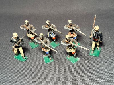 six figurines de soldats armés de lances et de boucliers, sur des socles verts