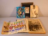 Trois livres sont posés sur une table, à côté d'une photo représentant une calèche.