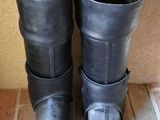 pair of black leather boots sitting on top of a tile floor