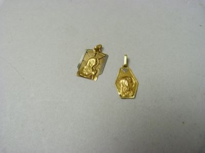 two small gold pendants with a picture of jesus on them