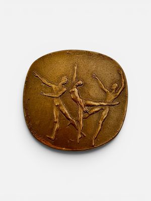 une image représentant une plaque en bronze sur fond blanc, sur laquelle figurent deux danseurs