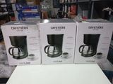 three boxes of coffee makers sitting on a table in a store