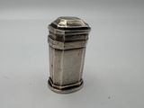 une salière ancienne en métal plaqué argent posée sur une surface blanche