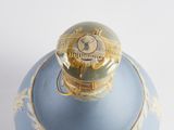 a blue vase with a gold lid on a white surface