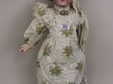 une vieille poupée en porcelaine aux cheveux bruns, vêtue d'une robe et chaussée de souliers