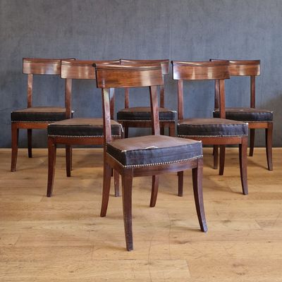 Quatre chaises en bois sont alignées contre un mur dans une pièce.
