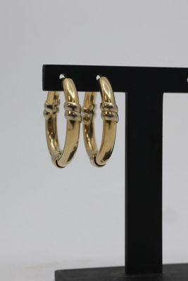 pair of gold tone hoop earrings on a black stand