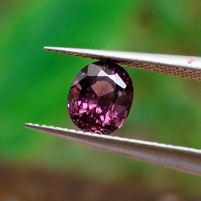 quelqu'un tient une paire de pinces ornées d'un diamant violet