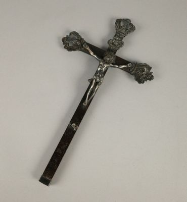 une croix en métal munie d'un manche en bois, posée sur une table