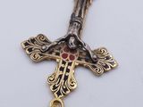a gold cross with a red stone in the center