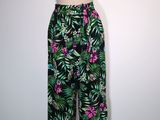 un pantalon à imprimé tropical noir et vert, orné de fleurs roses